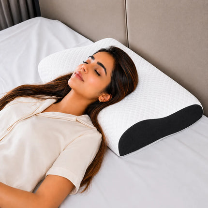 Woman lying on a bed with a white pillow featuring a black wedge