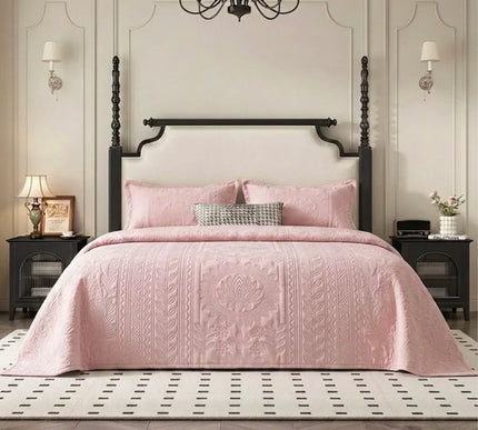Pink quilted cover on a bed in a stylish bedroom with a chandelier and wall sconces.