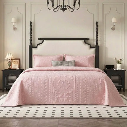 Pink quilted cover on a bed in a stylish bedroom with a chandelier and wall sconces.