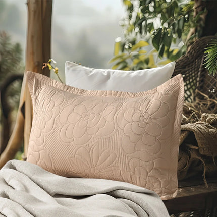 Quilted beige pillow on a textured surface with a blurred natural background