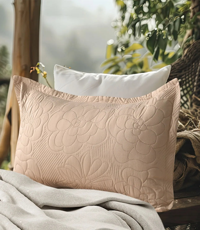 Quilted beige pillow on a textured surface with a blurred natural background