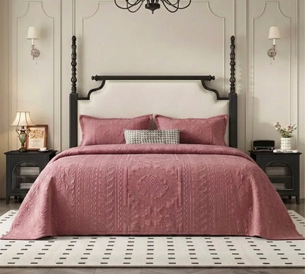 Bedroom with a four-poster bed covered in a pink quilt, nightstands, and a chandelier.