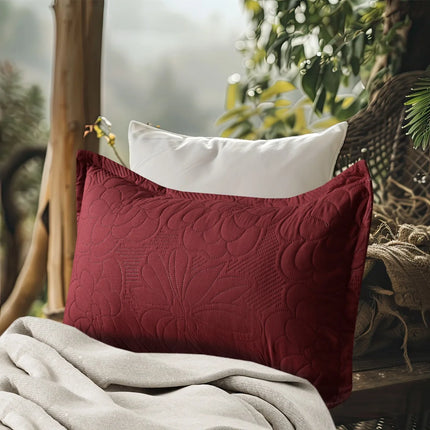 Red textured pillow and white pillow on a wooden bench with a blurred natural background