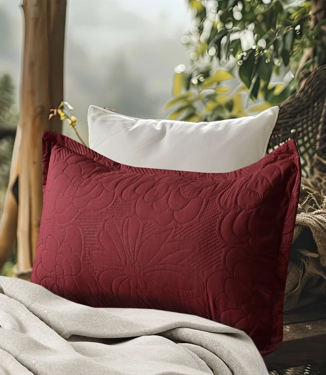 Red textured pillow and white pillow on a wooden bench with a blurred natural background