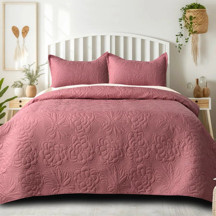 Pink floral quilt set on a bed in a bedroom with plants and decor.