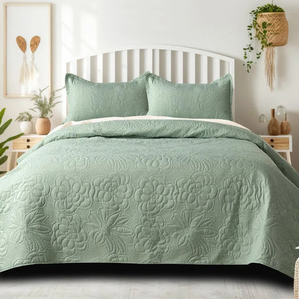 Green quilted bedspread on a bed in a well-lit bedroom with plants and decor.