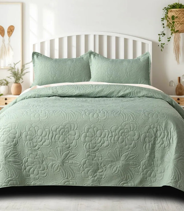 Green quilted bedspread on a bed in a well-lit bedroom with plants and decor.