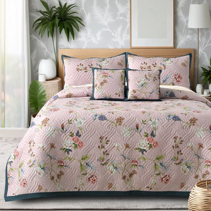 Floral quilt set on a bed in a bedroom with plants and decor.
