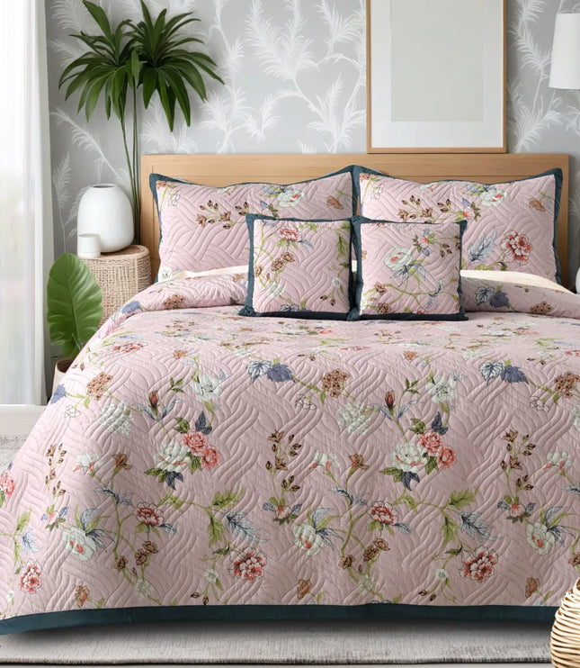 Floral quilt set on a bed in a bedroom with plants and decor.