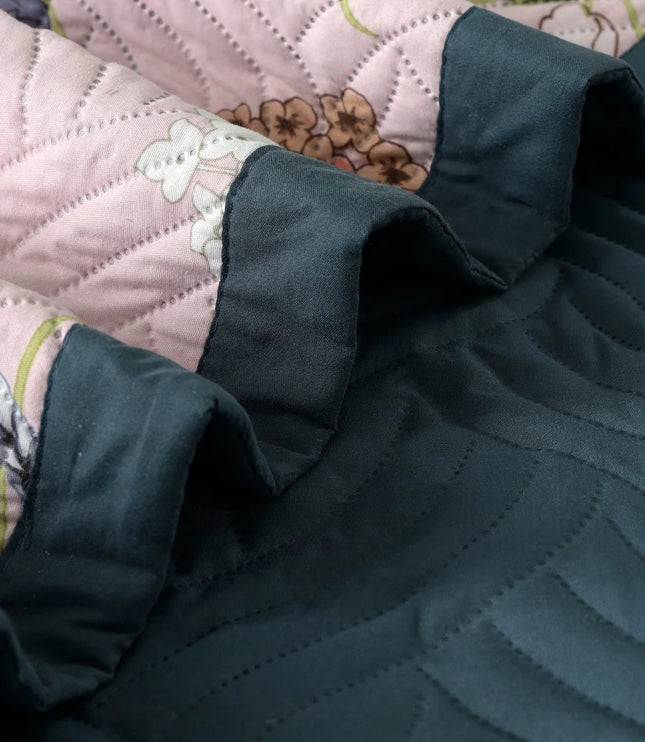 Dark green quilted fabric on a floral-patterned bedspread