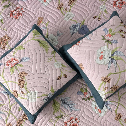 Floral quilt with two matching pillows on a matching fabric background