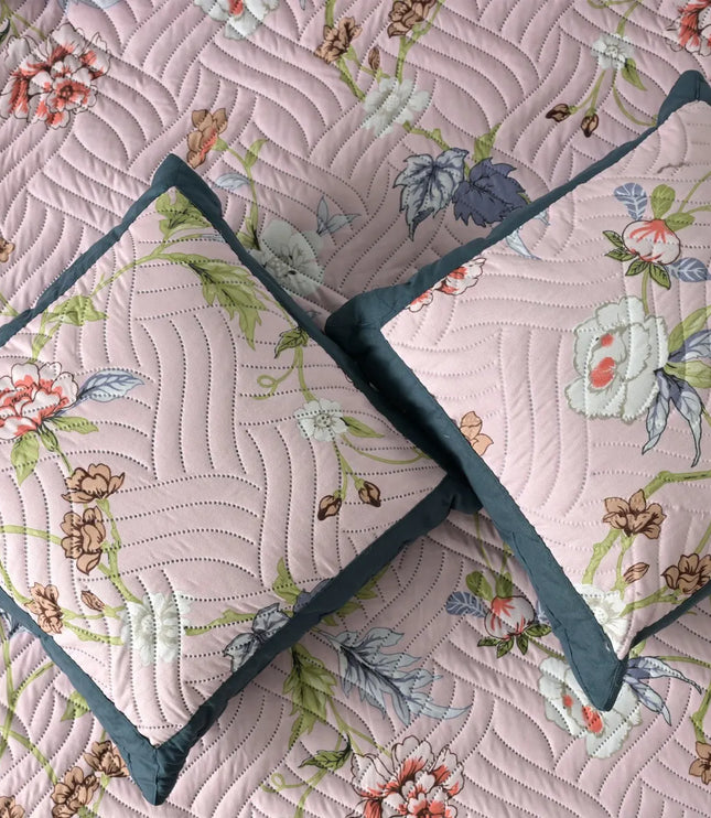 Floral quilt with two matching pillows on a matching fabric background