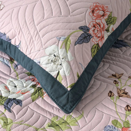 Floral quilt with green border on a matching fabric background