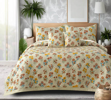 Floral patterned bedding set on a bed with decorative pillows and plants in the background.