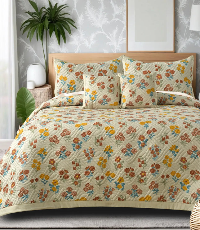 Floral patterned bedding set on a bed with decorative pillows and plants in the background.