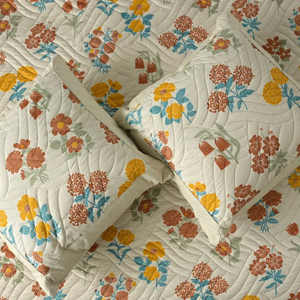 Floral patterned quilt with pillows on a matching fabric background