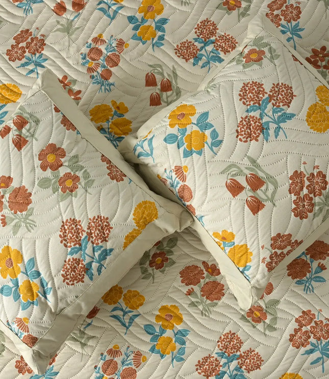 Floral patterned quilt with pillows on a matching fabric background