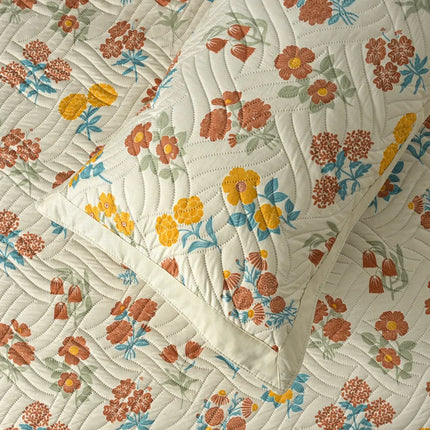 Floral patterned quilt with orange, yellow, and blue flowers on a white background