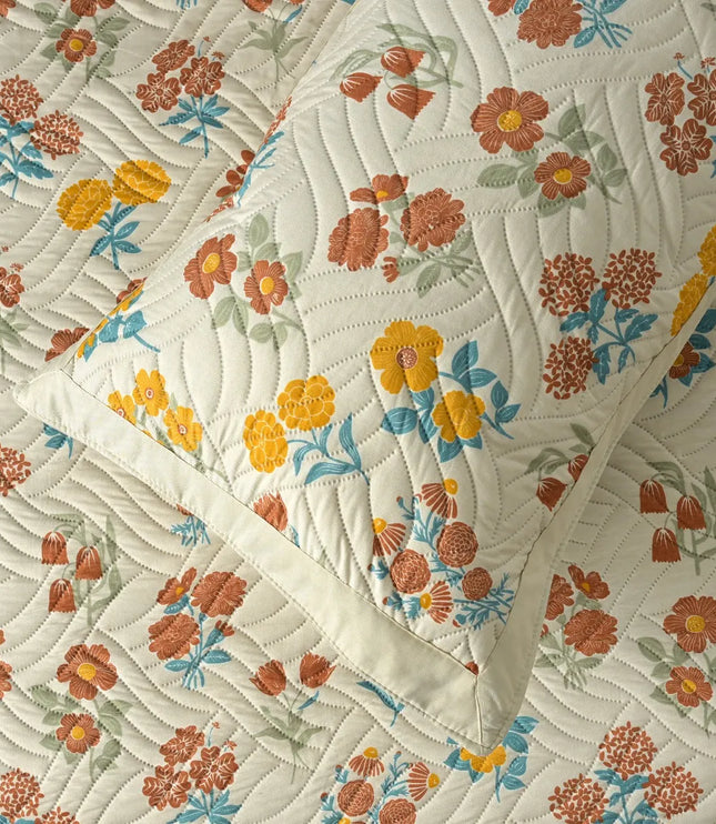 Floral patterned quilt with orange, yellow, and blue flowers on a white background