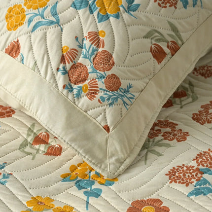 Floral quilt with orange, blue, and green flowers on a beige background