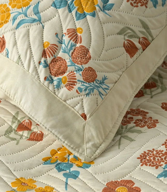 Floral quilt with orange, blue, and green flowers on a beige background