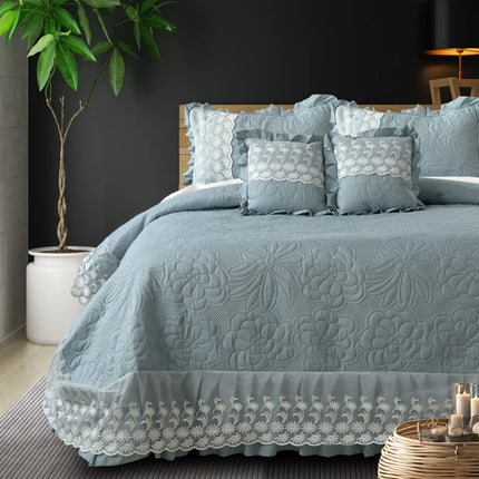 Blue textured bedspread with lace details on a bed in a bedroom setting.