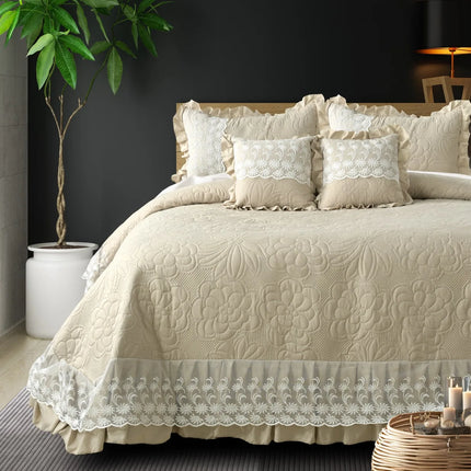 Beige quilted bedspread with lace details on a bed in a bedroom setting.