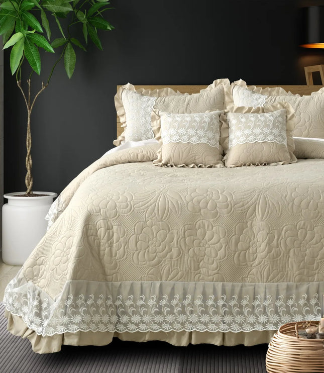 Beige quilted bedspread with lace details on a bed in a bedroom setting.