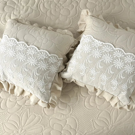 Two decorative pillows with lace trim on a textured beige surface
