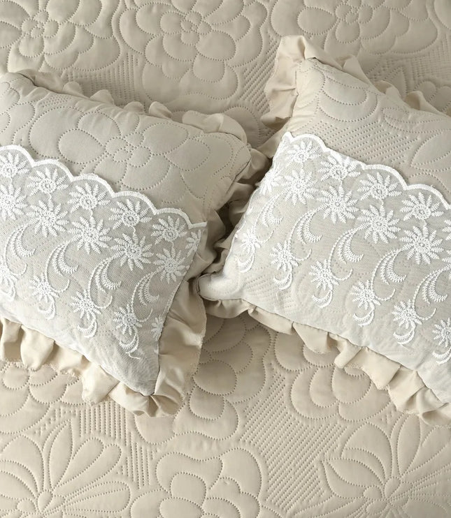 Two decorative pillows with lace trim on a textured beige surface