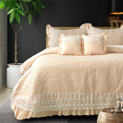 Beige quilted bedspread with lace trim on a bed in a bedroom setting.