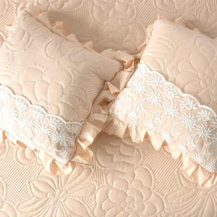 Two decorative pillows with lace trim on a textured beige surface