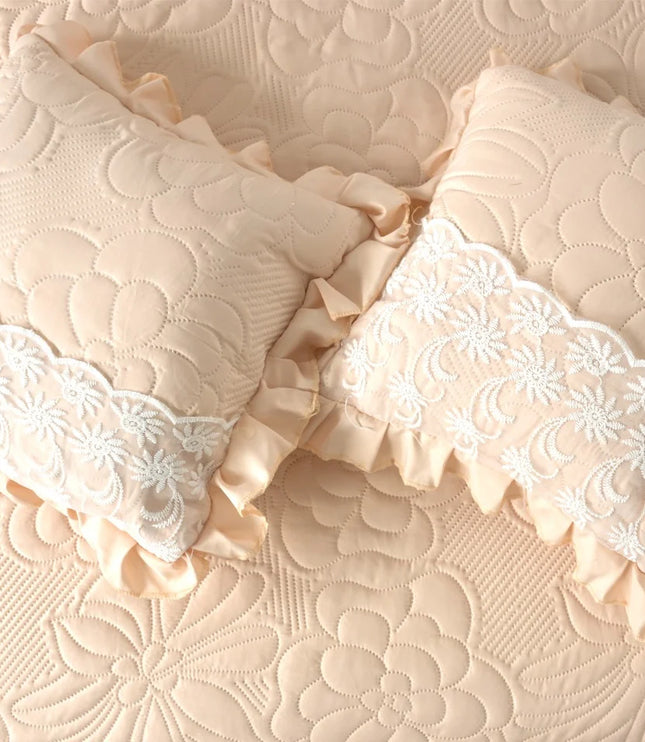 Two decorative pillows with lace trim on a textured beige surface