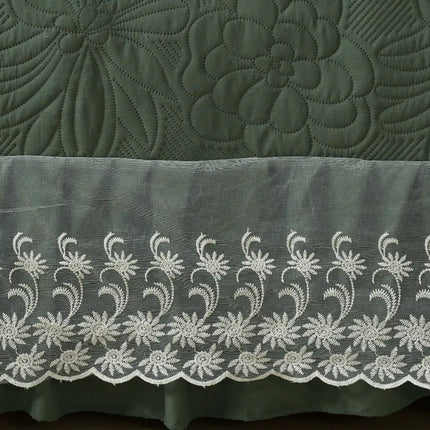 Green quilt with floral embroidery and a white lace trim.