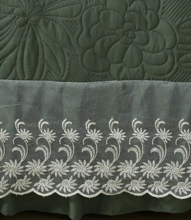 Green quilt with floral embroidery and a white lace trim.