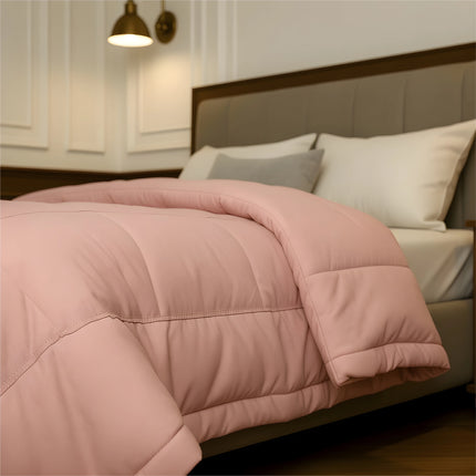 Bedroom with a neatly made bed featuring baby pink bedding and wooden furniture.