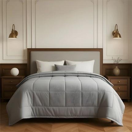 Gray comforter on a bed in a bedroom setting with wooden furniture and wall sconces.