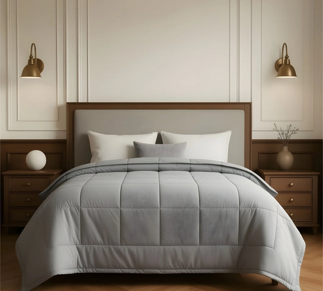 Gray comforter on a bed in a bedroom setting with wooden furniture and wall sconces.