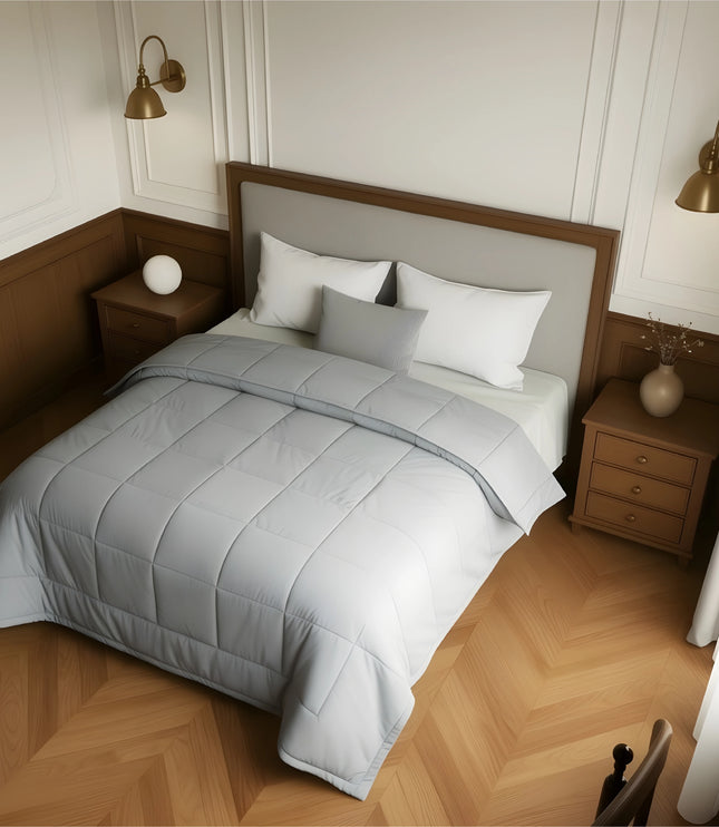 Bedroom with a neatly made bed featuring gray bedding and wooden furniture.