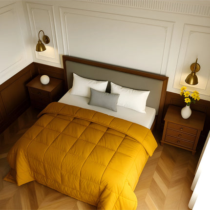 Bedroom with a neatly made bed featuring yellow bedding and wooden furniture.