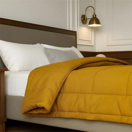 Bedroom with a neatly made bed featuring yellow bedding and wooden furniture.