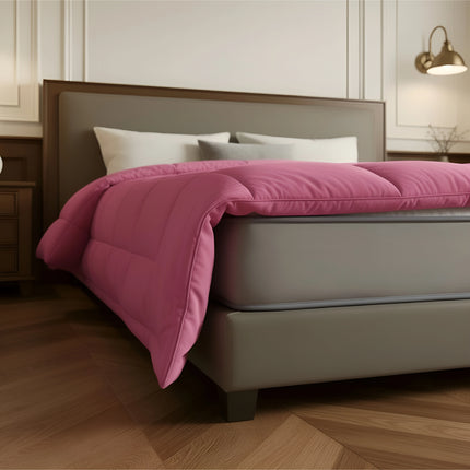 Bed with pink comforter and white pillows in a bedroom setting