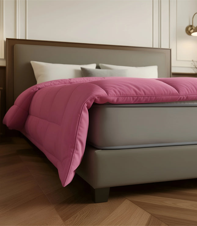 Bed with pink comforter and white pillows in a bedroom setting