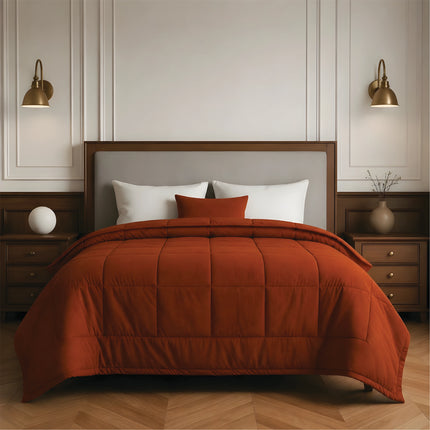 Bedroom with a neatly made bed featuring rust bedding and wooden furniture.