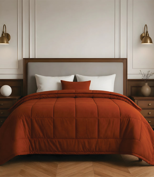 Bedroom with a neatly made bed featuring rust bedding and wooden furniture.