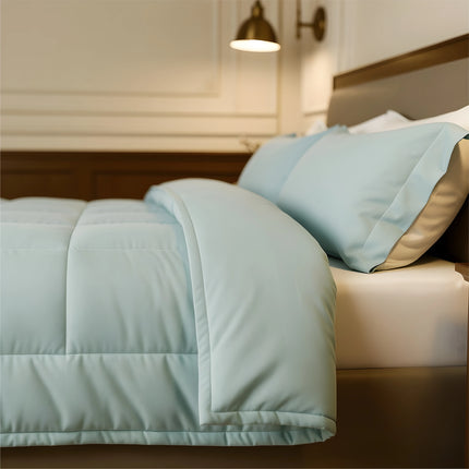 Bed with light blue comforter and pillows in a bedroom setting