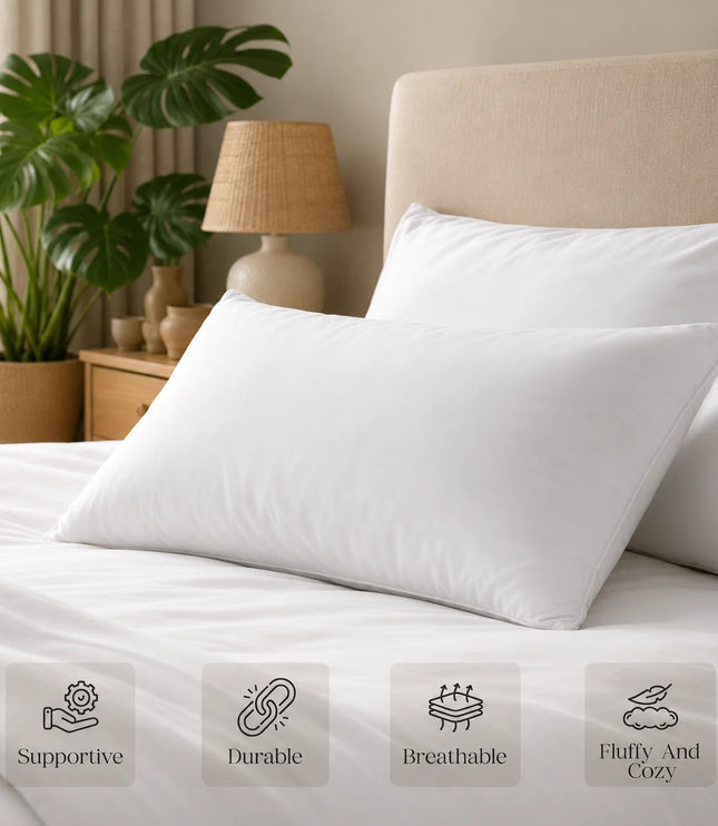 White pillows on a bed with a lamp and plant in the background, featuring icons and text about pillow qualities.